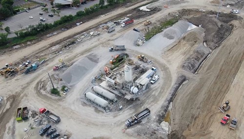 Aerial view into construction area with portable concrete plant and work vehicles